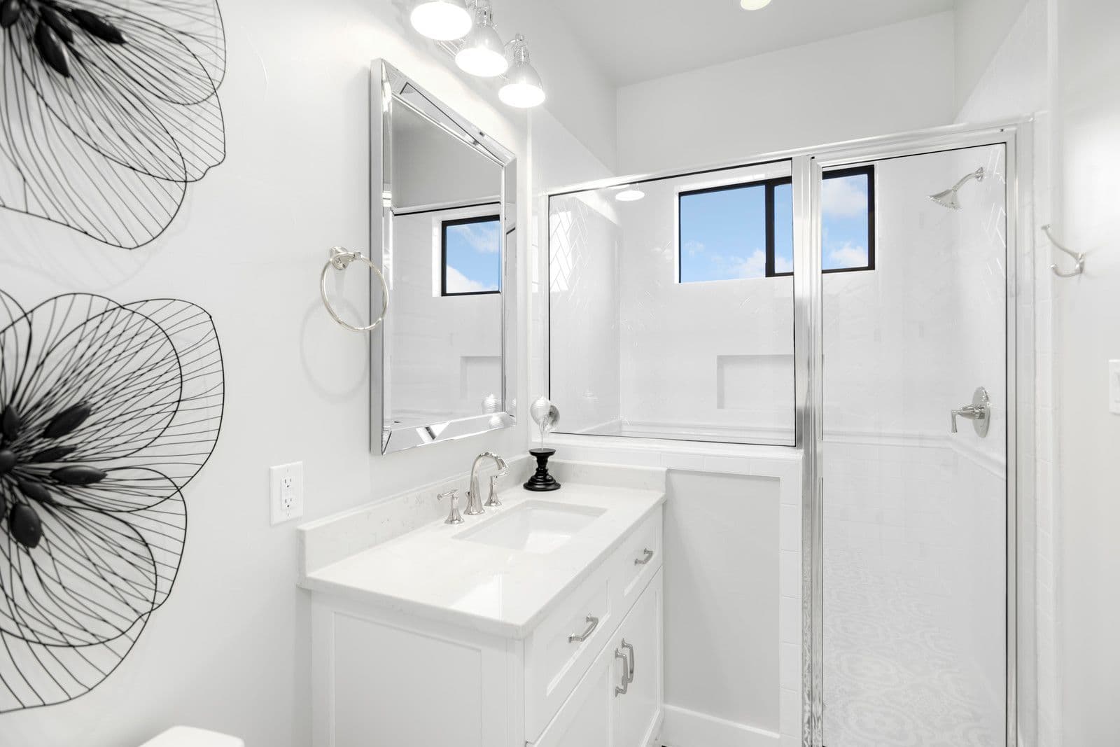 White bathroom with a framed glass shower and framed vanity mirror