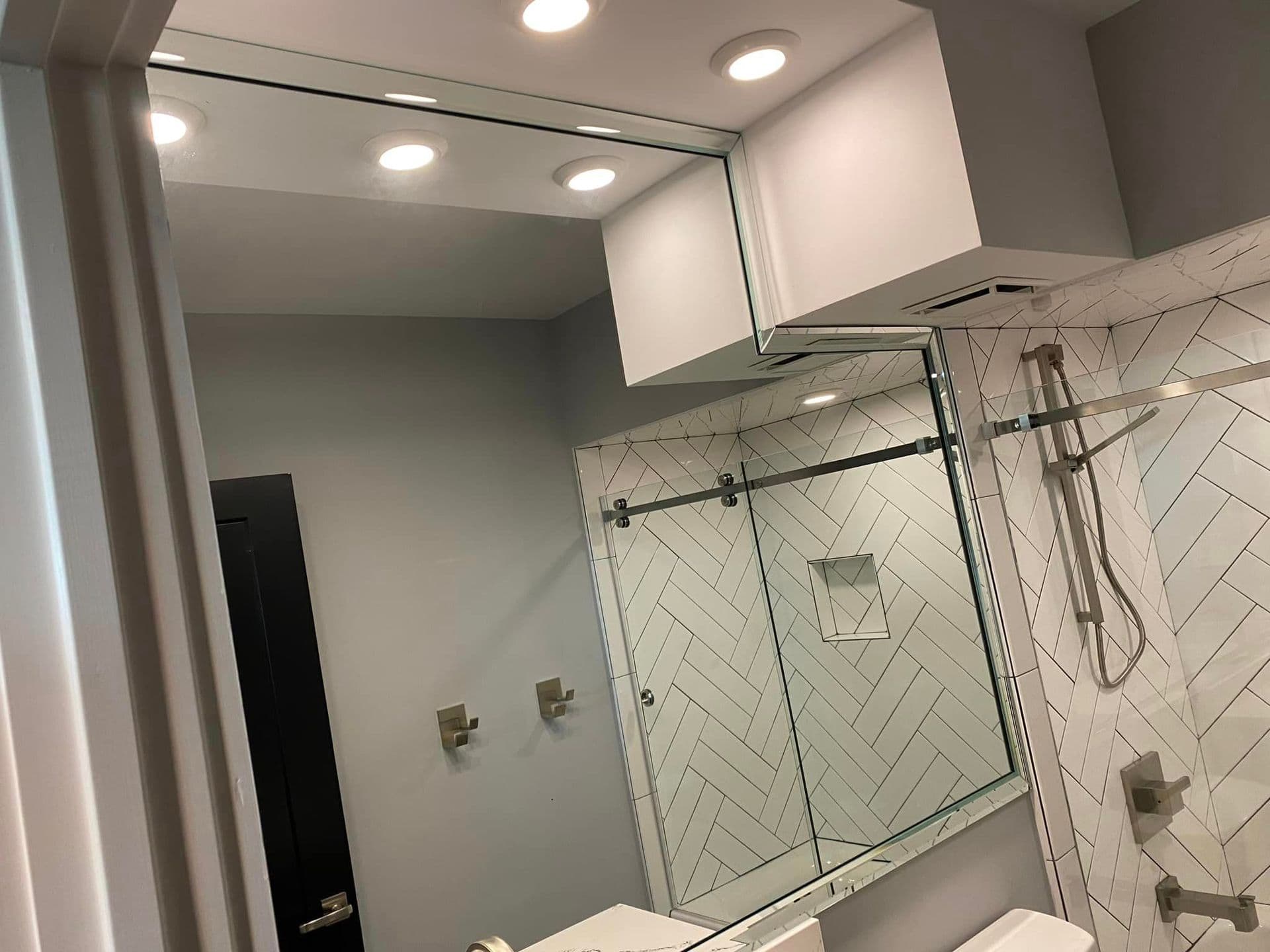 Large frameless bathroom mirror above a glass shower enclosure