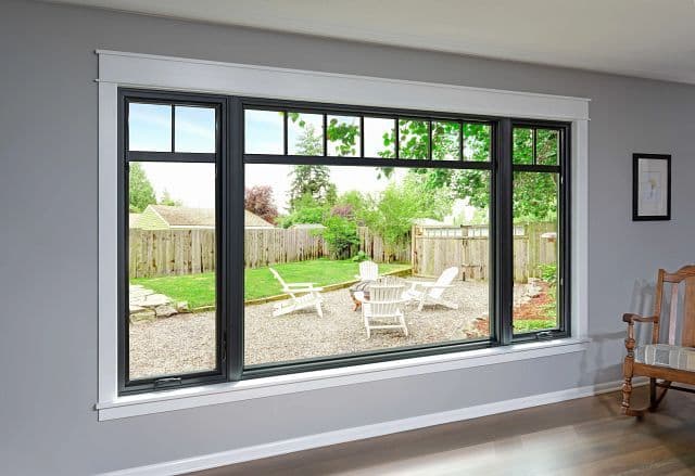 Living room with a large black-framed replacement window looking out onto a back yard